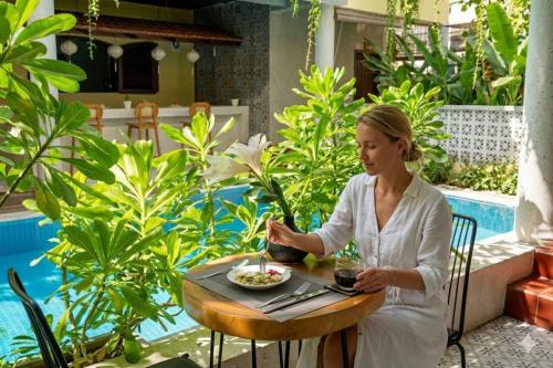 een vrouw aan een tafel met een kom eten bij La ALBA An Bang Beach Villa in Hội An