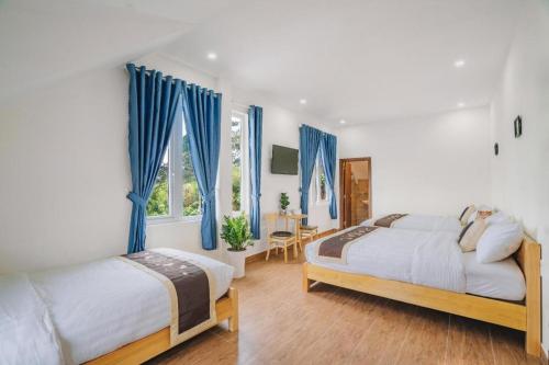- 2 lits dans une chambre dotée de rideaux bleus dans l'établissement May Trang Villa, à Xuan An
