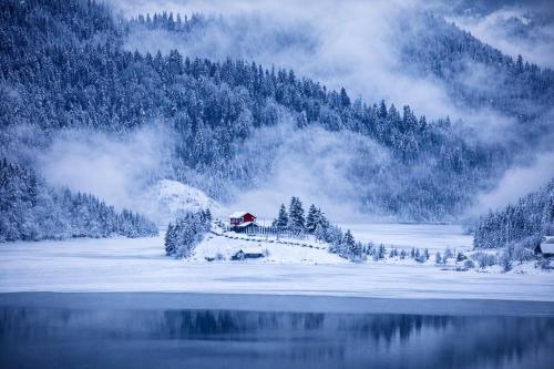 a house in the snow next to a lake at Cazare Colibița Casa Lipan cu jacuzzi, foișor și loc de joacă in Colibiţa