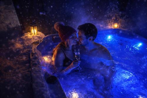 a man and a woman sitting in a hot tub at Aurora Igloo Village Ylläs - Hot Tub in Ylläsjärvi