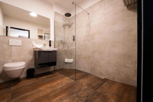 a bathroom with a shower and a toilet and a sink at PEN Smart Hotel in Türkheim