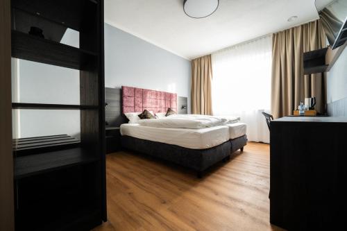 a bedroom with a bed and a large window at PEN Smart Hotel in Türkheim
