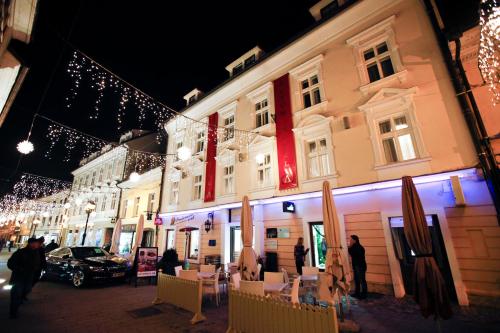 um grupo de pessoas do lado de fora de um edifício com luzes de Natal em Hotel Actum em Kranj