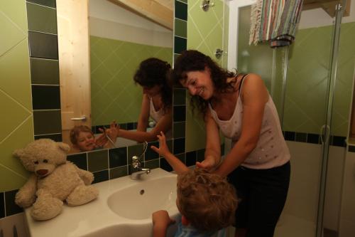 a woman standing in a bathroom with a child in front of a sink at Camping Al Lago Ledro in Ledro