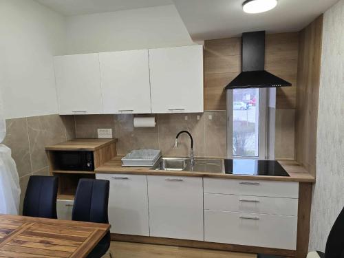 a kitchen with white cabinets and a sink and a table at Prenočišca Dany 3 in Dravograd