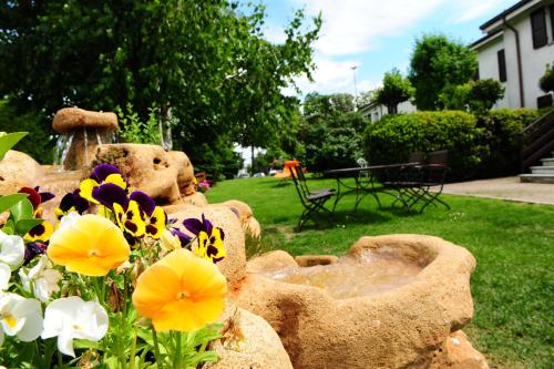 a garden with a teddy bear statue and flowers at Il Carrettino Country Hotel in Tortona