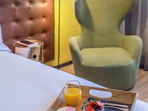 un vassoio di frutta e un bicchiere di succo d'arancia su un tavolo di Pullman Santiago El Bosque a Santiago