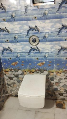 a bathroom with a toilet and a mural of dolphins at Hotel Pawar Palace Mahurgad in Māhūr