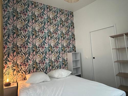 une chambre avec un grand lit avec un papier peint fleuri dans l'établissement le Limo: logement cosy en hyper centre, à Périgueux