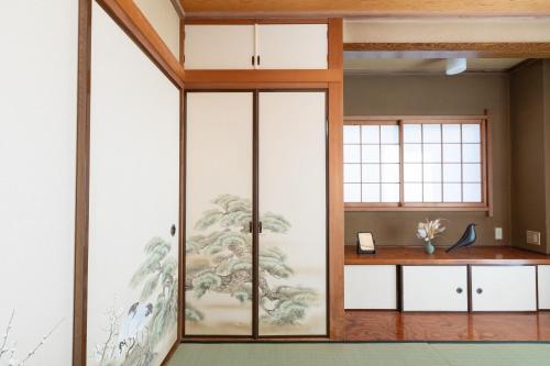 a room with sliding glass doors with a painting on the wall at Kotori Ayase in Tokyo