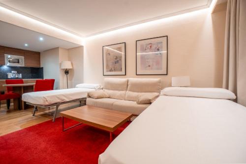 ein Zimmer mit zwei Betten und einer Couch und einem Tisch in der Unterkunft Aparto-Hotel Rosales in Madrid
