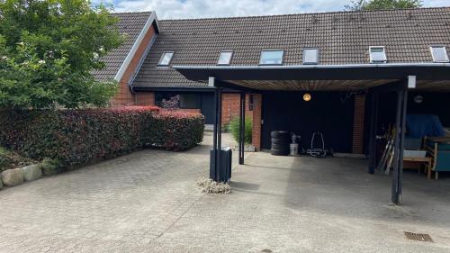 a house with a garage with a roof at Rækkehus tæt på skov, sø og by in Viborg