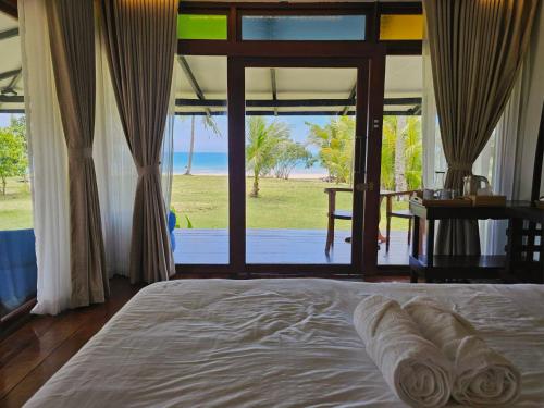 a bedroom with a bed with a view of the ocean at BAIBAI Long Beach in New Agutaya