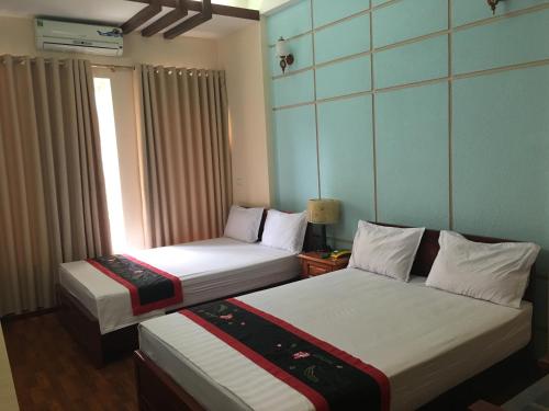 two beds in a hotel room with a window at Sunrise Hotel in Hanoi