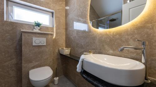 a bathroom with a sink and a toilet and a mirror at House Vidovic by Villas Guide in Mlinište