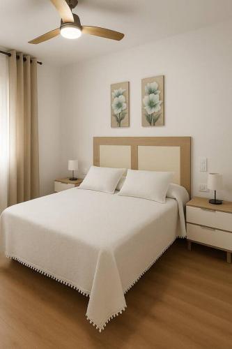 a bedroom with a large white bed with a ceiling fan at Alojamiento Baeza - Chicharro in Baeza