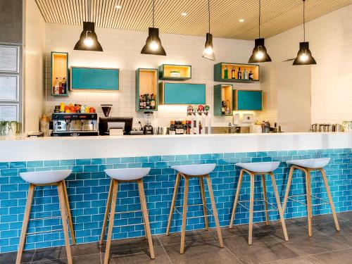 a bar with three stools in front of a counter at ibis Styles East Perth in Perth