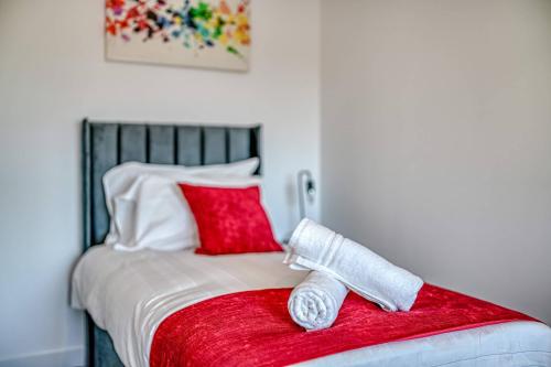a bed with two red pillows and a red blanket at 1-BR Flat in Eccles - 1 Minute Walk to Train & Tram Station - Sleeps 3 in Manchester