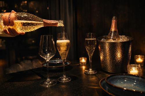 een persoon die champagne in glazen op een tafel schenkt bij Aurora Igloo Village Ylläs Luna Suite - Hot Tub in Ylläsjärvi