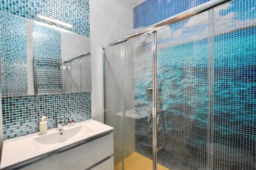 a bathroom with a sink and a shower with blue tiles at Velaria Boutique Apartment in Monopoli