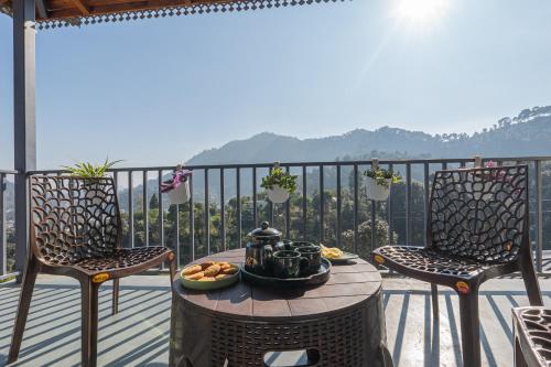 a table and chairs on a balcony with a bowl of food at SaffronStays The Kumaoni Abode in Bhīm Tāl