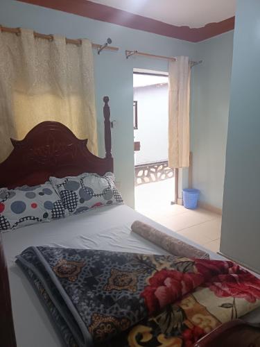 een slaapkamer met een bed met een houten hoofdeinde bij Delight motel in Ishaka