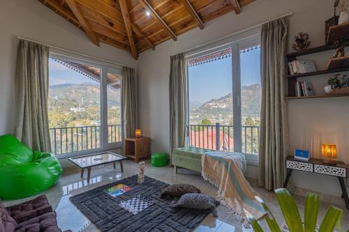 a living room with large windows and a balcony at SaffronStays The Kumaoni Abode in Bhīm Tāl