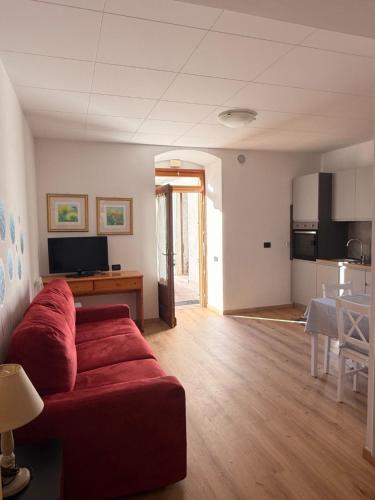 un salon avec un canapé rouge et une cuisine dans l'établissement Monolocale a Molveno, à Molveno