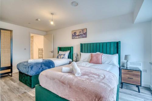 a bedroom with two beds with green headboards at 2-BR Near Salford Royal - City & Town Centre View - 1 Minute to Train & Tram Station - Sleeps 6 in Manchester