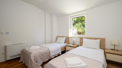 two beds in a white room with a window at Villa Dida Bozo by Villas Guide in Blace