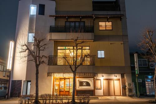 a tall building with two trees in front of it at Guest House Ouka in Takayama