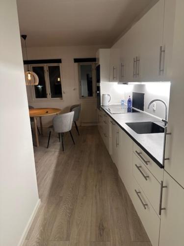 a kitchen with white cabinets and a wooden floor at 11F 1 Th in Vejle