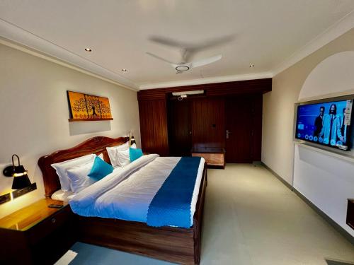 een slaapkamer met een groot bed en een flatscreen-tv bij ALOHA DIVINE GANGES APARTMENTS with INFINITY POOL in Rishīkesh