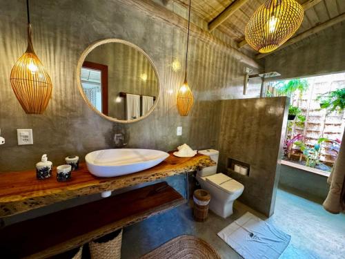 ein Badezimmer mit Waschbecken, Toilette und Spiegel in der Unterkunft Casa Preguiça Corumbau in Corumbau