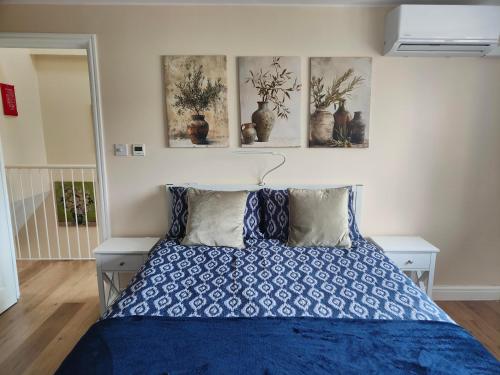 a bedroom with a blue bed with three pictures on the wall at Clifton House O2 & Excel Rooms with private bathroom and Breakfast option in London