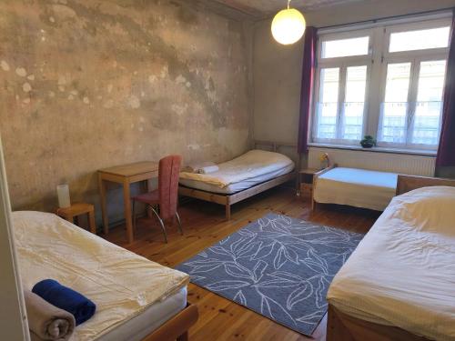 a room with two beds and a table and a window at Grosses Privatzimmer mit Altbau-Charme in Leipzig