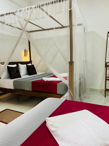 a bedroom with two beds with mosquito nets at Shaa Home Stay Sigiriya in Sigiriya