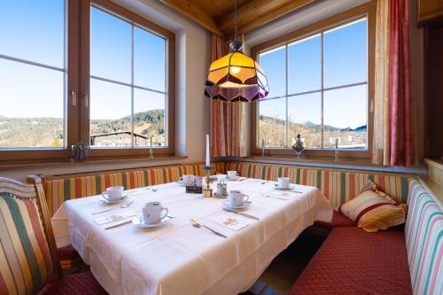 a dining room with a table in a room with windows at Hotel Austria Wildschönau & Wildschönau Premium Card in Niederau