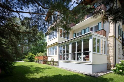a white house with a porch and a yard at Villa Marienhof in Annenheim