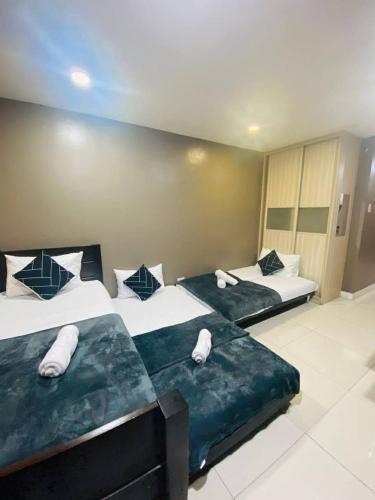 two beds in a hotel room with towels on them at The Highland Condotel in Baguio