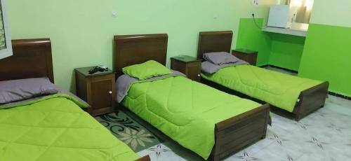 Zimmer mit 3 Betten und grüner Bettwäsche in der Unterkunft Hotel el djawhara in Melika