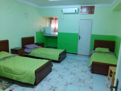 zwei Betten in einem Zimmer mit grünen Wänden in der Unterkunft Hotel el djawhara in Melika
