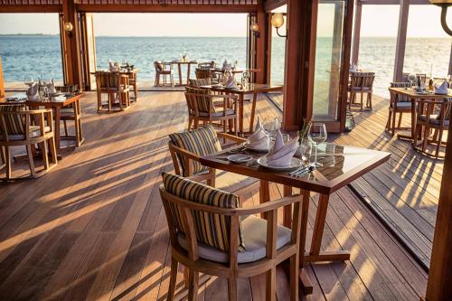 a restaurant with tables and chairs and the ocean at Hurawalhi Island Resort in Kuredu