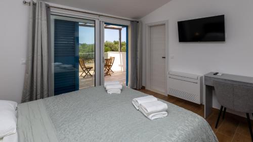 a bedroom with a bed with a desk and a balcony at Villa Olea by Villas Guide in Blace