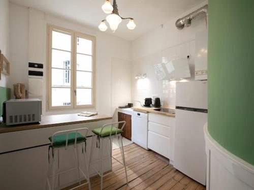 una cucina con mobili bianchi e sgabelli verdi di La luciole a Périgueux