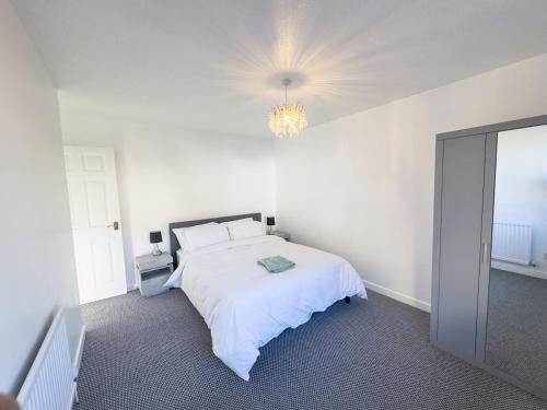 a white bedroom with a bed and a chandelier at Spacious Newport Home Near ICC & Local Attractions in Newport