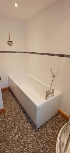 eine Badewanne mit einem Wasserhahn im Bad in der Unterkunft Bwlch Cottage in Gwaynynog