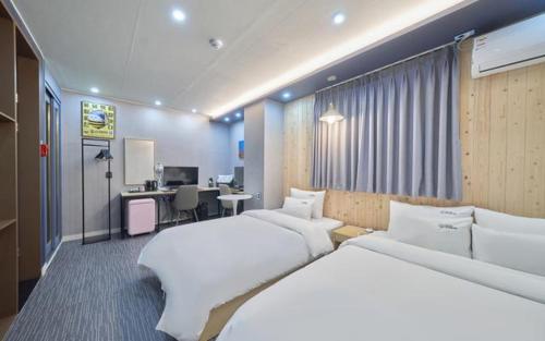 a hotel room with two beds and a desk at Hotel Haeseong in Changwon