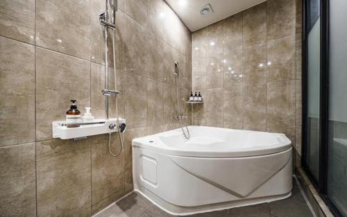 a bathroom with a tub and a toilet and a sink at Hotel Haeseong in Changwon