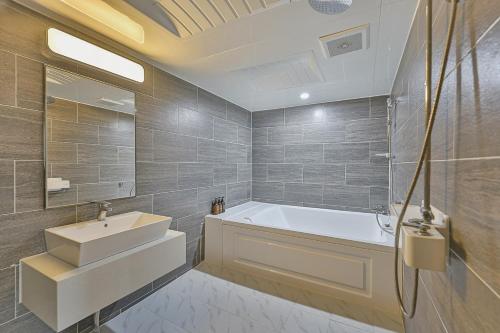 a bathroom with a white tub and a sink at Palace Hotel in Ulsan